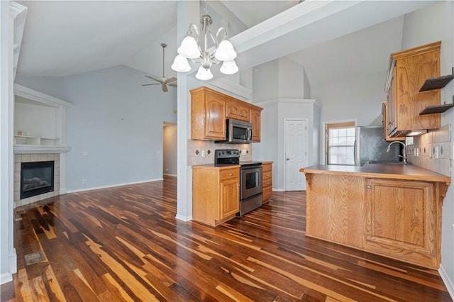 kitchen featuring sink, dark hardwood / wood-style floors, stainless steel appliances, a tiled fireplace, and backsplash