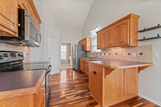 kitchen with a breakfast bar, sink, appliances with stainless steel finishes, dark hardwood / wood-style flooring, and kitchen peninsula