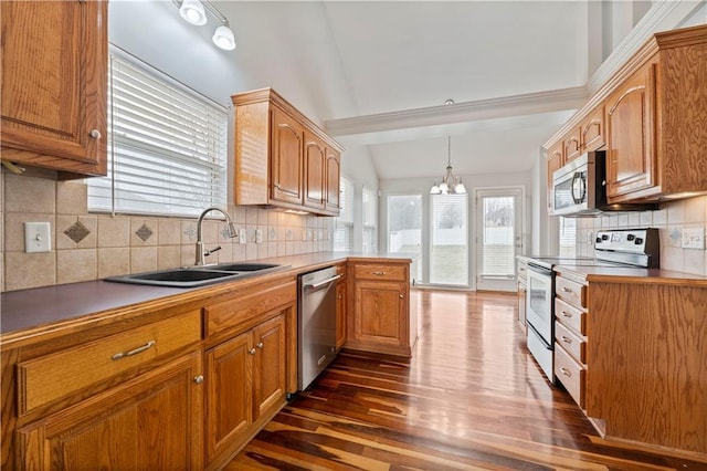 kitchen with pendant lighting, tasteful backsplash, sink, stainless steel appliances, and dark wood-type flooring