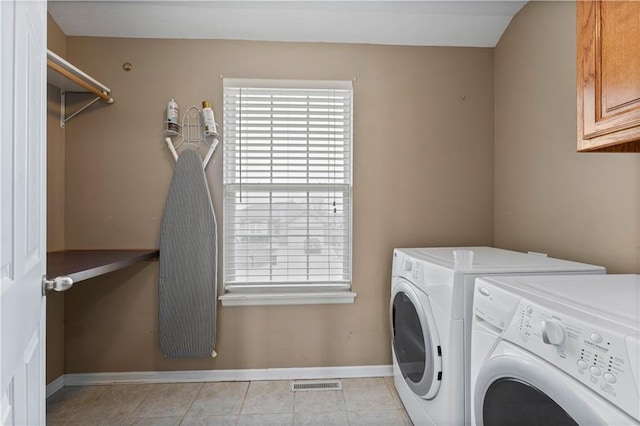 clothes washing area featuring light tile patterned flooring, cabinets, and washing machine and dryer