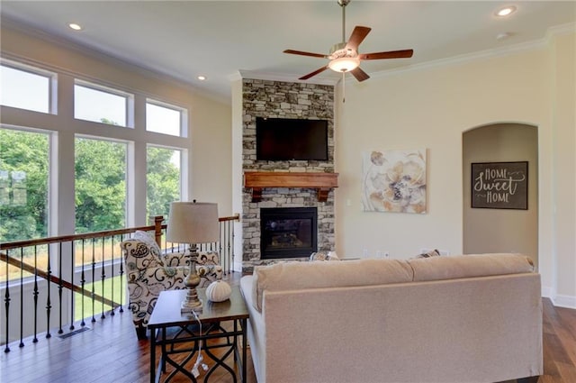 living room featuring dark hardwood / wood-style flooring, crown molding, a fireplace, and ceiling fan