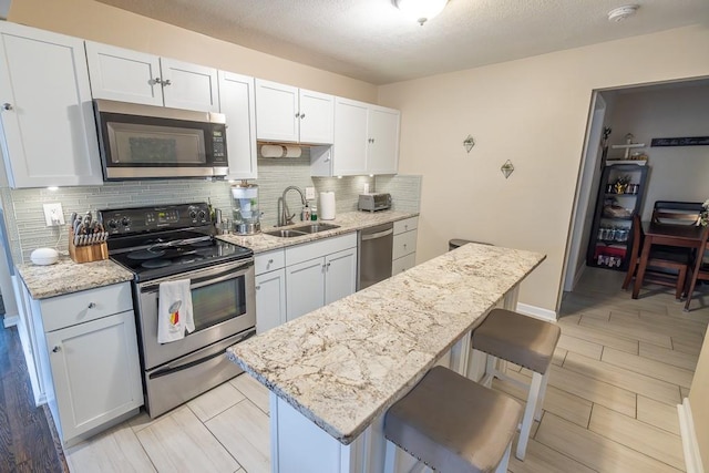 kitchen with sink, a kitchen breakfast bar, white cabinets, and appliances with stainless steel finishes