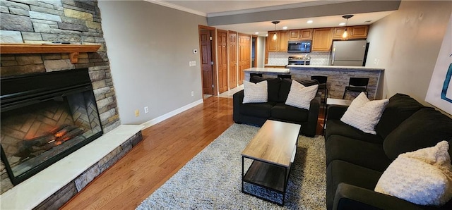 living room featuring a stone fireplace, light hardwood / wood-style flooring, and ornamental molding