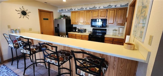 kitchen featuring a kitchen breakfast bar, kitchen peninsula, and black appliances