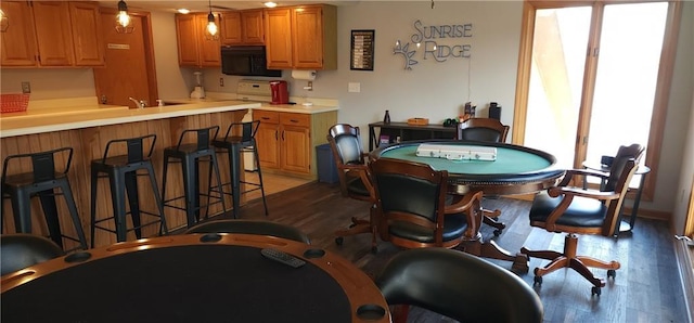 interior space featuring pendant lighting, dark wood-type flooring, and a kitchen bar