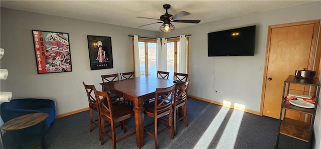 dining space with ceiling fan and dark colored carpet