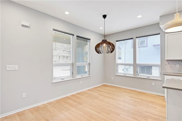 unfurnished dining area featuring light wood-style floors, plenty of natural light, baseboards, and recessed lighting