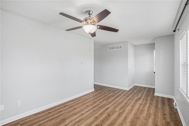 unfurnished room with baseboards, plenty of natural light, visible vents, and wood finished floors