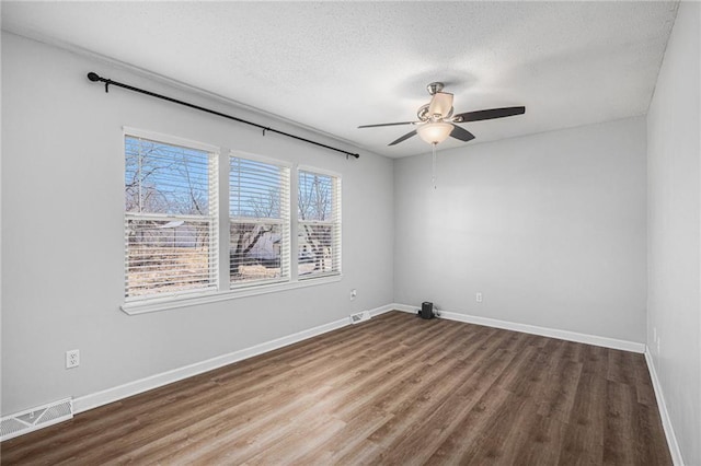 unfurnished room featuring visible vents, a ceiling fan, a textured ceiling, wood finished floors, and baseboards