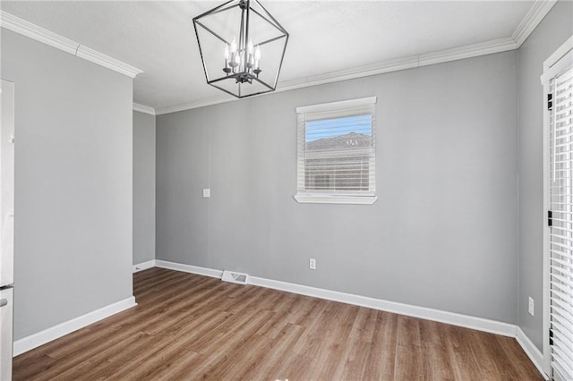 unfurnished dining area featuring baseboards, visible vents, wood finished floors, crown molding, and a notable chandelier