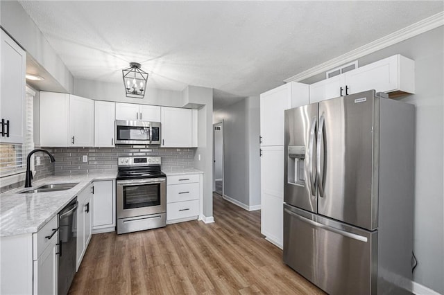 kitchen featuring appliances with stainless steel finishes, white cabinetry, light wood-style floors, and decorative backsplash