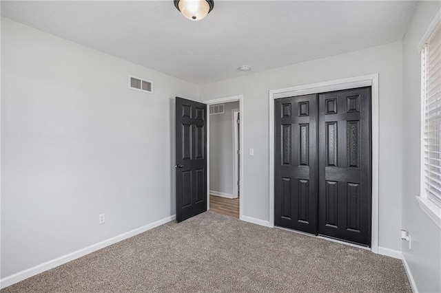 unfurnished bedroom with a closet, carpet, visible vents, and baseboards