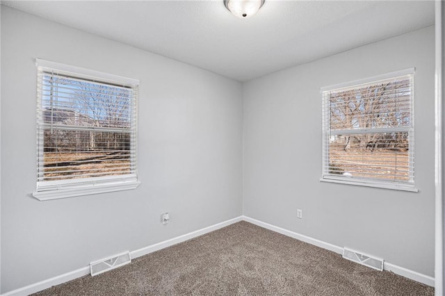 spare room featuring baseboards, visible vents, and carpet flooring