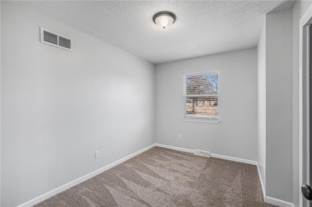 carpeted spare room with a textured ceiling, visible vents, and baseboards