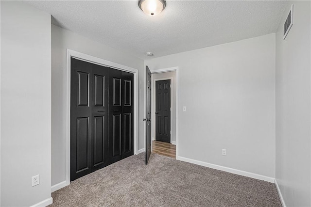 unfurnished bedroom with carpet floors, a textured ceiling, baseboards, and a closet