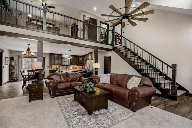 living room featuring a high ceiling, hardwood / wood-style flooring, and ceiling fan with notable chandelier