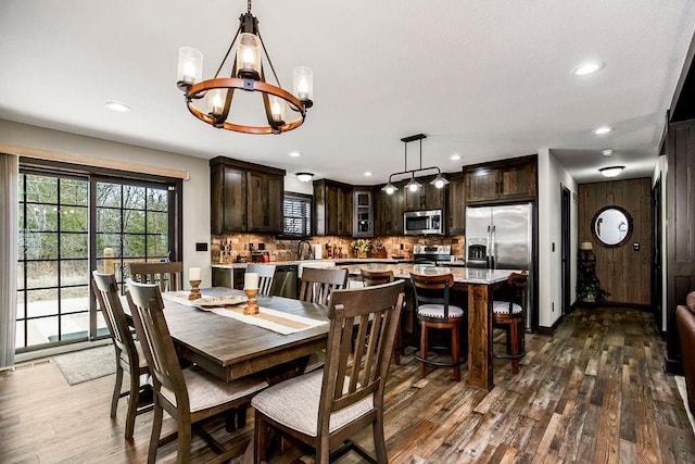 dining area featuring sink, dark wood-type flooring, and a chandelier