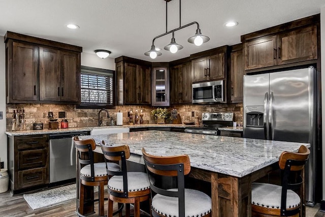 kitchen featuring stainless steel appliances, a kitchen island, sink, and dark brown cabinetry