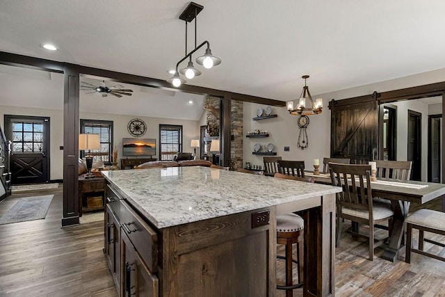 kitchen with hanging light fixtures, vaulted ceiling, a barn door, and a center island