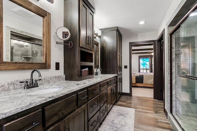 bathroom with hardwood / wood-style flooring, vanity, and a shower with door