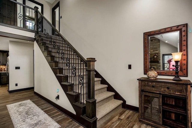 staircase featuring wood-type flooring and high vaulted ceiling