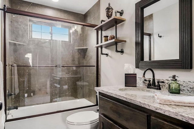 full bathroom featuring vanity, shower / bath combination with glass door, and toilet