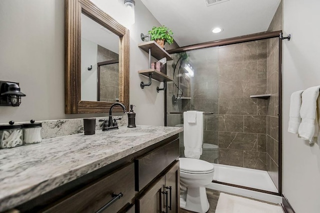 bathroom featuring vanity, toilet, and a shower with shower door