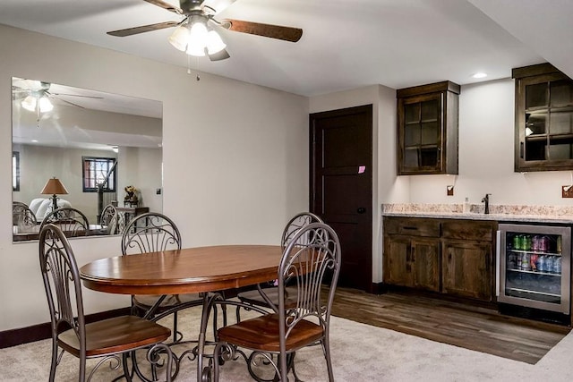 dining space with ceiling fan, beverage cooler, light hardwood / wood-style floors, and indoor wet bar