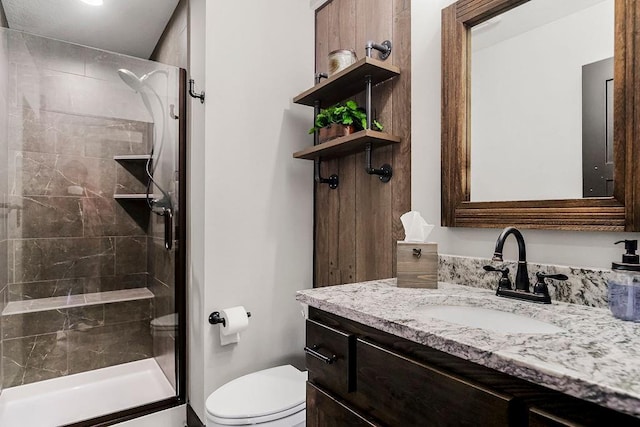 bathroom featuring vanity, a tile shower, and toilet