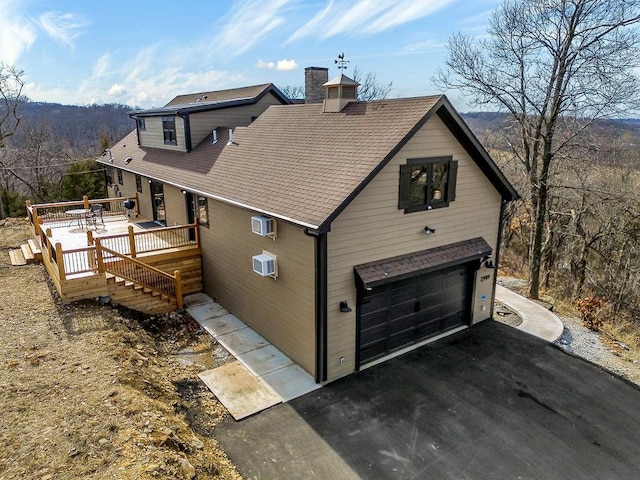 view of front of property featuring a garage, a deck, and a wall mounted air conditioner