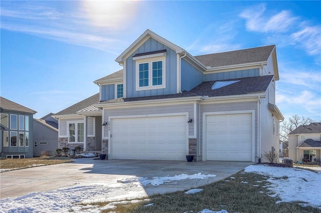 view of front facade featuring stone siding, board and batten siding, an attached garage, and driveway