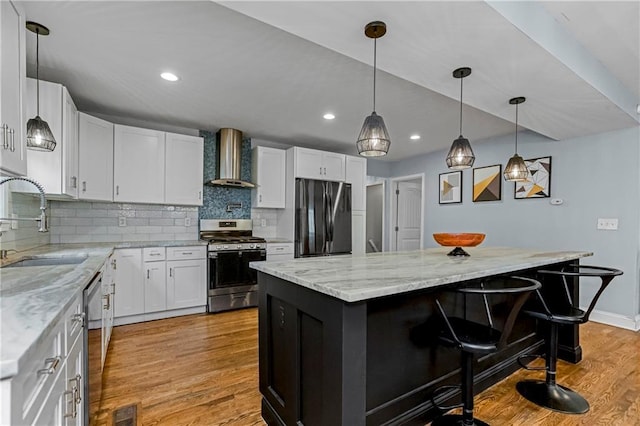 kitchen featuring wall chimney exhaust hood, white cabinetry, appliances with stainless steel finishes, and a kitchen island