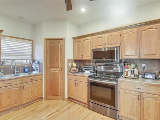 kitchen featuring sink, stainless steel appliances, tasteful backsplash, light hardwood / wood-style floors, and light brown cabinetry