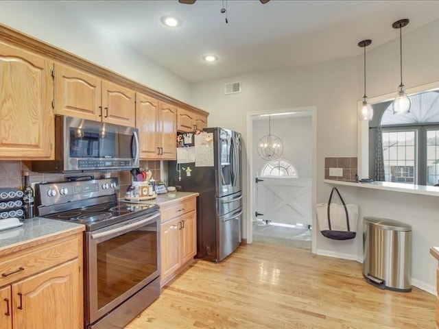 kitchen with stainless steel appliances, decorative light fixtures, decorative backsplash, and light wood-type flooring