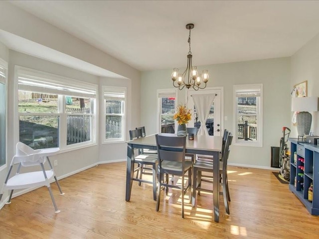 dining area featuring an inviting chandelier, a healthy amount of sunlight, and light hardwood / wood-style flooring