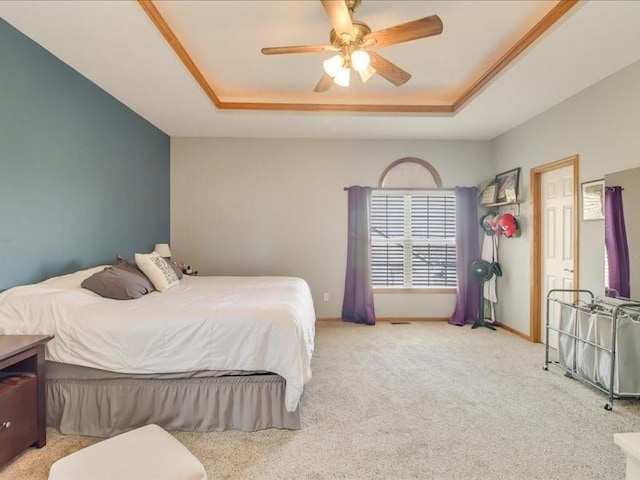 carpeted bedroom with a raised ceiling and ceiling fan