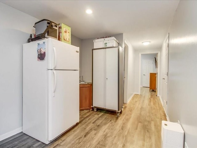 kitchen featuring white cabinets, sink, white fridge, and light wood-type flooring