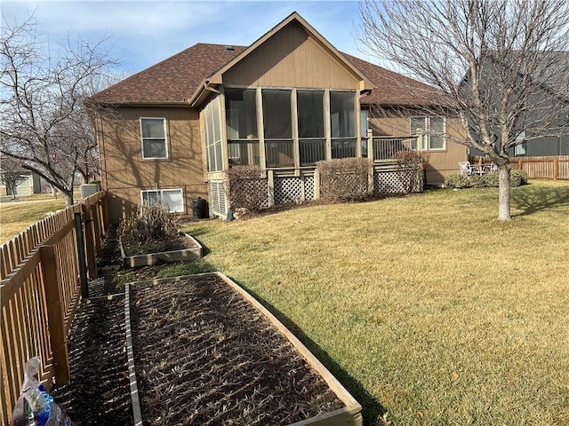 rear view of property featuring a yard, a sunroom, and central air condition unit