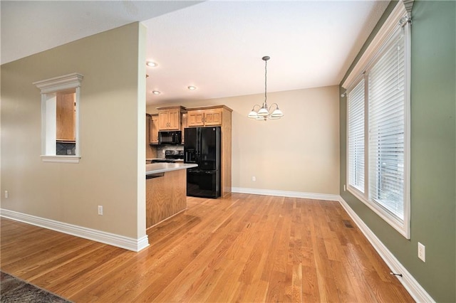 kitchen featuring tasteful backsplash, a chandelier, pendant lighting, light hardwood / wood-style floors, and black appliances