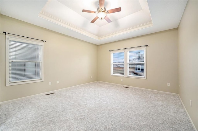 carpeted spare room with crown molding, ceiling fan, and a tray ceiling