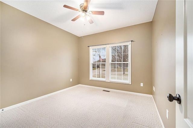 carpeted empty room featuring a ceiling fan, visible vents, a textured ceiling, and baseboards