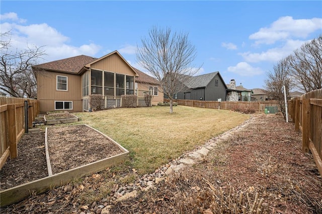 rear view of house featuring a yard, a sunroom, a fenced backyard, and a vegetable garden