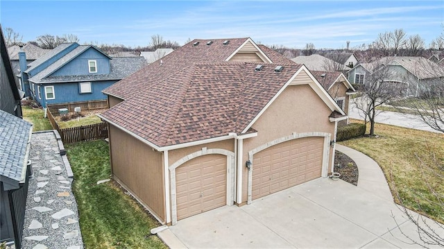 view of front of property featuring an attached garage, fence, driveway, stucco siding, and a front yard