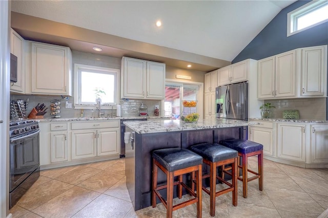 21465 W 180th St, Olathe, KS 66062 - kitchen with appliances with stainless steel finishes, decorative backsplash, a kitchen bar, white cabinets, and high vaulted ceiling