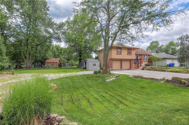 21465 W 180th St, Olathe, KS 66062 - view of green lawn featuring asphalt driveway, an attached garage, and a storage shed