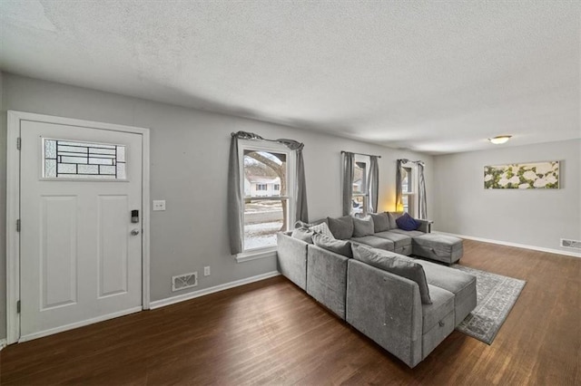 living room with visible vents, dark wood finished floors, a textured ceiling, and baseboards