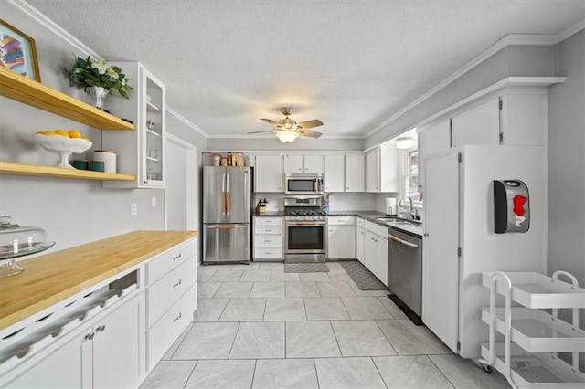 kitchen featuring a sink, white cabinetry, appliances with stainless steel finishes, crown molding, and ceiling fan