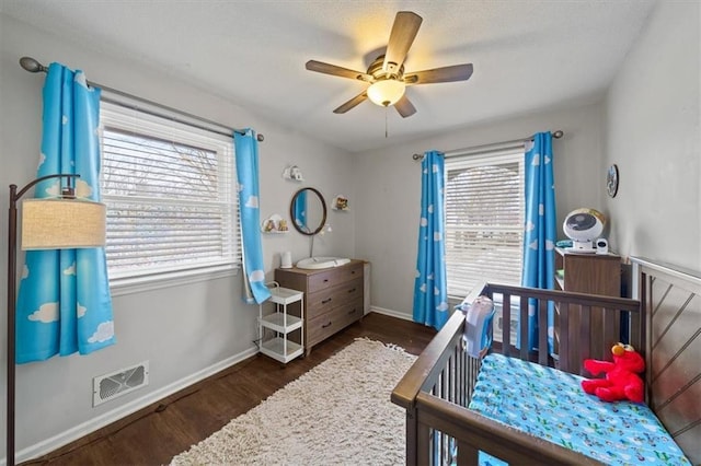 bedroom with ceiling fan, visible vents, baseboards, and wood finished floors