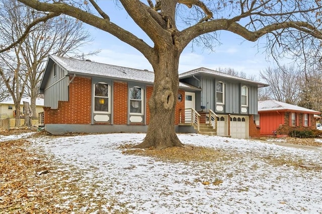 tri-level home with brick siding, board and batten siding, an attached garage, and fence