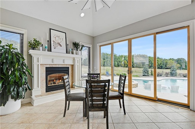 dining space featuring lofted ceiling, a tile fireplace, and light tile patterned flooring